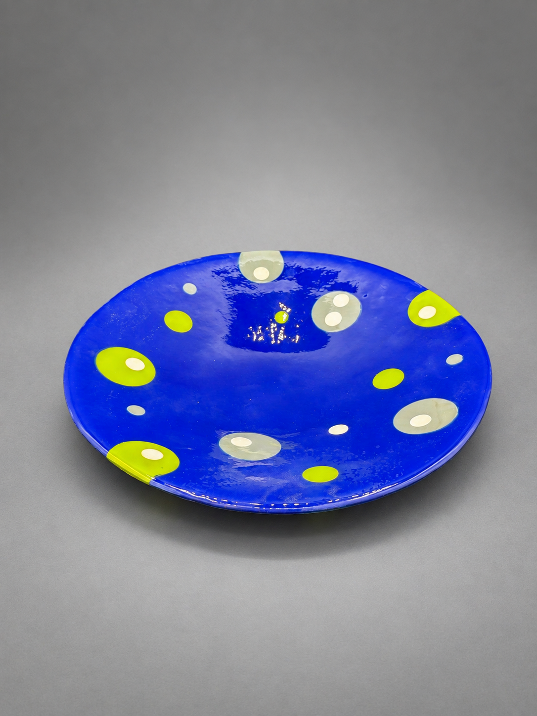 Bubble Dance Platter, a cobalt-blue fused-glass platter with chartreuse, gray, and creamy-white bubbles.