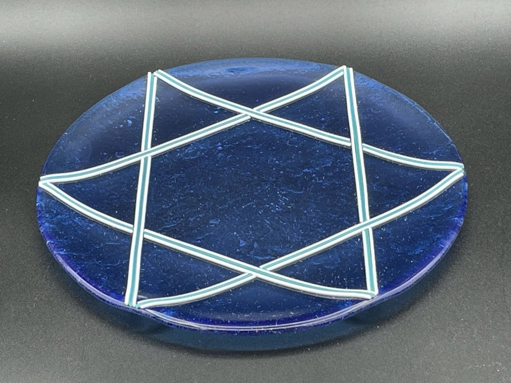 Star of David platter is perfect for any occasion like Shabbat challah, Hanukkah cookies, or Passover matzo. The platter is transparent blue with white and turquoise star.  Dimensions are approximately 10” (inches).