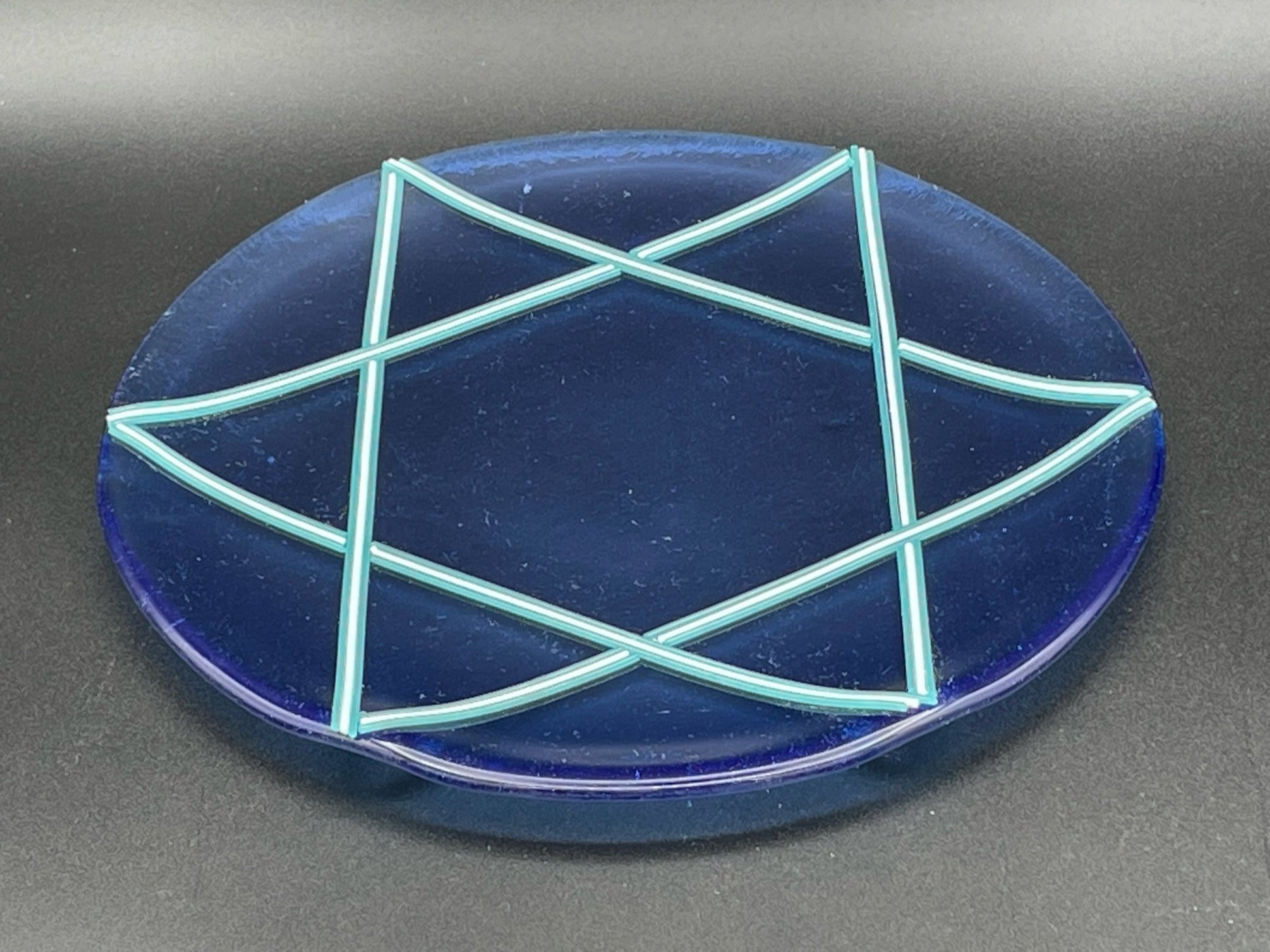Star of David platter is perfect for any occasion like Shabbat challah, Hanukkah cookies, or Passover matzo. The platter is transparent blue with turquoise and white star.  Dimensions are approximately 10” (inches).